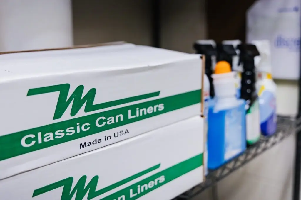 Shelves stocked with facility supply products including trash can liners and cleaning supplies