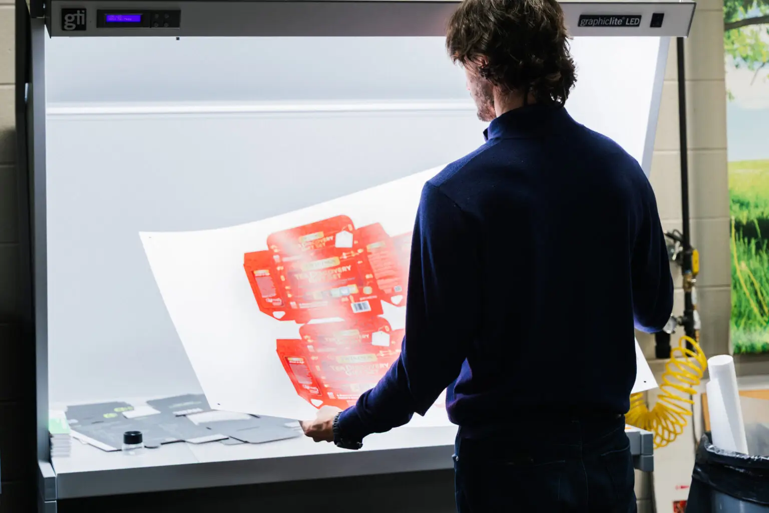 Morrisette Packaging designer reviewing custom packaging artwork under a light box